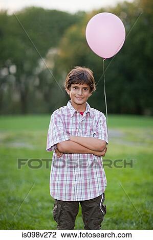 Stock Image - Boy at birthday party holding pink balloon. Fotosearch