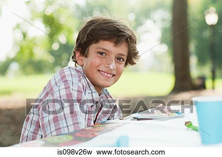Stock Photo - Boy at birthday party with birthday cake on his nose. Fotosearch