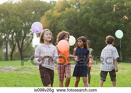Stock Image - Children at birthday party holding balloons. Fotosearch