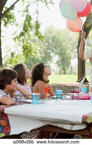 Stock Image - Children at birthday party with birthday cake. Fotosearch