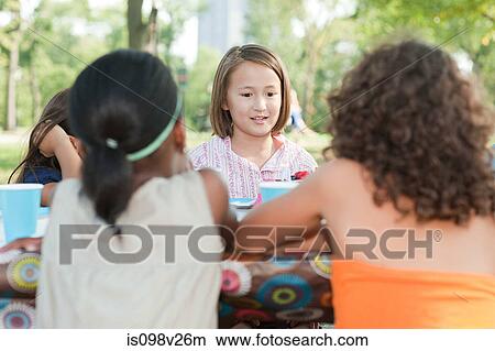Picture - Children sitting at picnic table at birthday party. Fotosearch