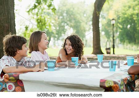 Children sitting at picnic table at birthday party View Large Photo Image Stock Photograph - Children sitting at picnic table at birthday party. Fotosearch