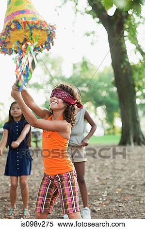 Stock Photography - Girl at birthday party hitting pinata. Fotosearch