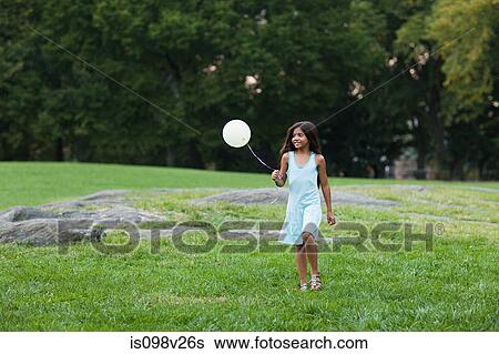Stock Photograph - Girl at birthday party holding balloon. Fotosearch