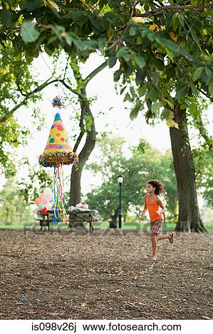 Stock Image - Girl at birthday party running past pinata. Fotosearch