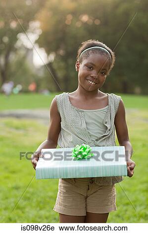Stock Image - Girl at birthday party with birthday present. Fotosearch