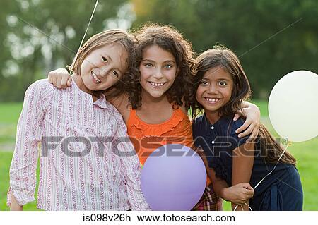 Stock Image - Girls at birthday party holding balloons. Fotosearch