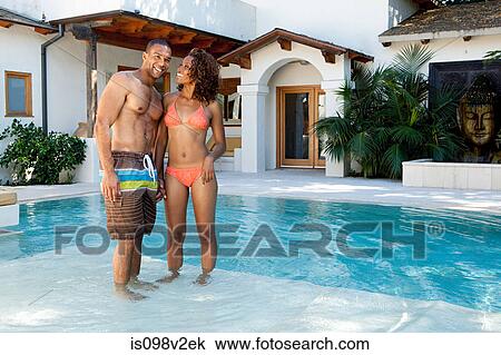 Stock Image - Couple standing in swimming pool. Fotosearch