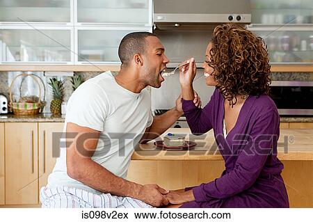 Stock Photo - Woman feeding cake to boyfriend. Fotosearch