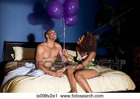 Stock Image - Young couple in bedroom with balloons. Fotosearch