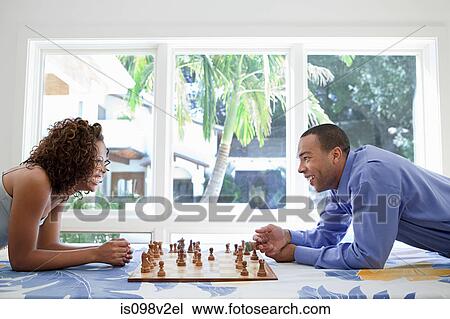 Stock Image - Young couple playing chess. Fotosearch