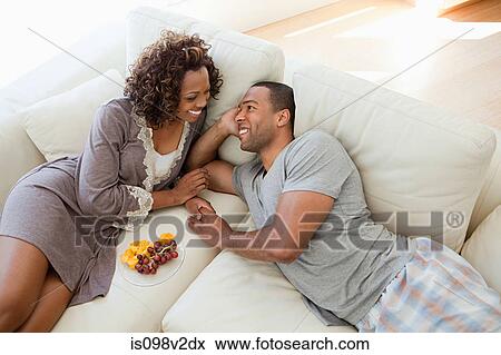 Stock Photo - Young couple relaxing on sofa. Fotosearch