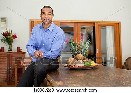 Stock Photo - Young man sitting on table. Fotosearch