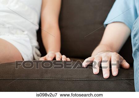 Close up of hands of couple on sofa View Large Photo Image Stock Photo - Close up of hands of couple on sofa. Fotosearch