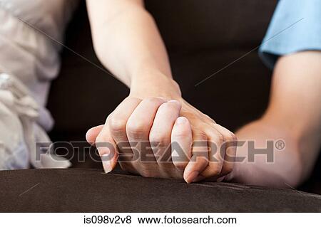 Stock Photo - Couple holding hands on sofa. Fotosearch