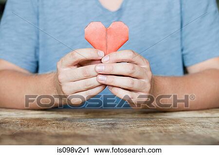 Stock Image - Person holding origami heart. Fotosearch