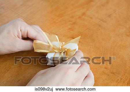 Stock Image - Person wrapping small gift. Fotosearch