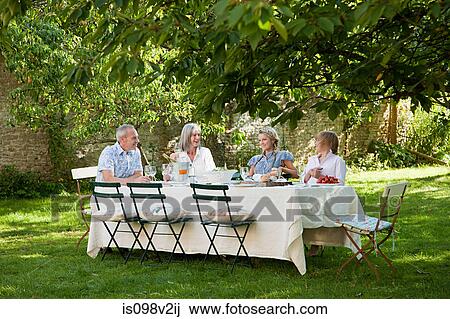 Stock Image - Family having lunch outdoors. Fotosearch