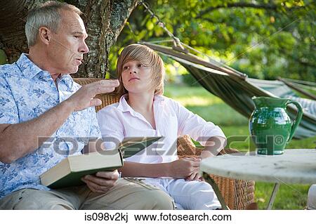 Stock Image - Father and son with book, in conversation. Fotosearch