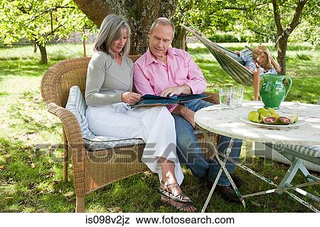 Mature couple outdoors looking at book View Large Photo Image Stock Photo - Mature couple outdoors looking at book. Fotosearch