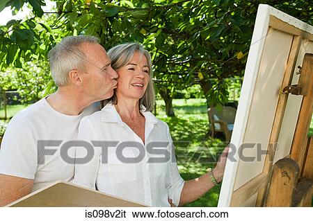Stock Photograph - Mature couple, woman painting at easel. Fotosearch