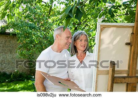 Stock Photograph - Mature couple, woman painting at easel. Fotosearch