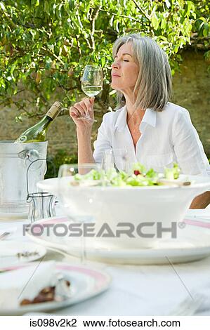 Mature woman holding glass of white wine View Large Photo Image Stock Image - Mature woman holding glass of white wine. Fotosearch