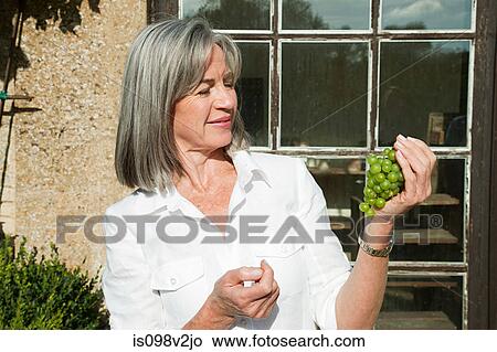 Picture - Mature woman holding grapes. Fotosearch
