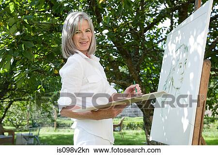 Picture - Mature woman painting at easel. Fotosearch
