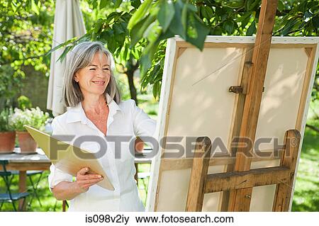 Stock Photo - Mature woman painting at easel. Fotosearch