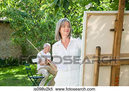 Stock Photography - Mature woman painting at easel. Fotosearch
