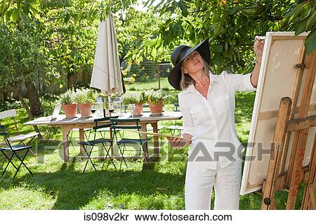 Stock Photography - Mature woman painting at easel. Fotosearch