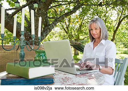 Stock Image - Mature woman using laptop. Fotosearch