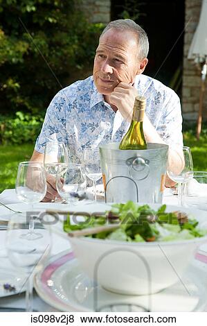 Senior man having lunch with wine outdoors View Large Photo Image Stock Photo - Senior man having lunch with wine outdoors. Fotosearch