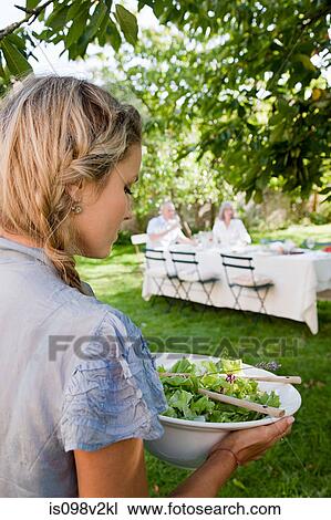 Stock Image - Young woman carrying bowl of salad. Fotosearch