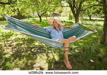 Stock Image - Young woman relaxing in hammock. Fotosearch