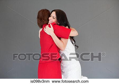 Picture - Daughter trying on wedding dress, embracing mother. Fotosearch
