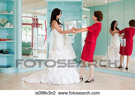 Stock Image - Daughter trying on wedding dress, holding hands. Fotosearch