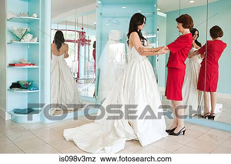 Stock Photo - Daughter trying on wedding dress, holding hands. Fotosearch