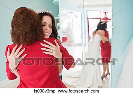 Stock Photography - Daughter trying on wedding dress, embracing mother. Fotosearch