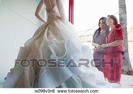 Stock Photo - Mother and daughter looking at wedding dress in shop window. Fotosearch