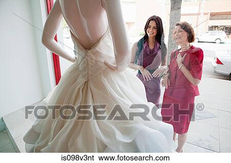 Stock Photograph - Mother and daughter looking at wedding dress in shop window. Fotosearch