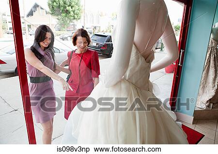Stock Photography - Mother and daughter looking at wedding dress in shop window. Fotosearch