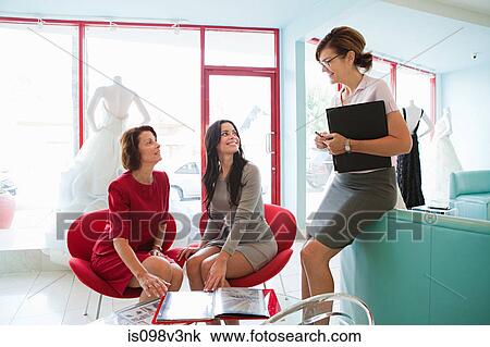 Stock Image - Mother and daughter talking to wedding dress designer. Fotosearch