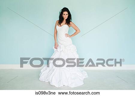 Stock Image - Young woman wearing white wedding dress, studio shot. Fotosearch