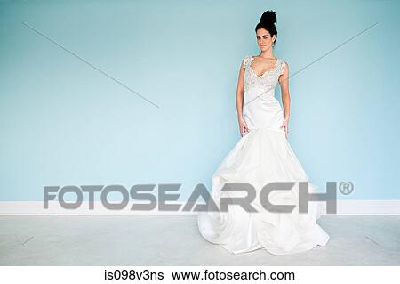 Stock Photograph - Young woman wearing white wedding dress, studio shot. Fotosearch