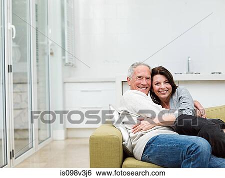 Mature couple embracing on sofa View Large Photo Image Stock Photograph - Mature couple embracing on sofa. Fotosearch