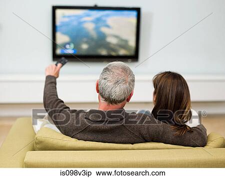 Mature couple sitting on sofa watching television View Large Photo Image Stock Photography - Mature couple sitting on sofa watching television. Fotosearch