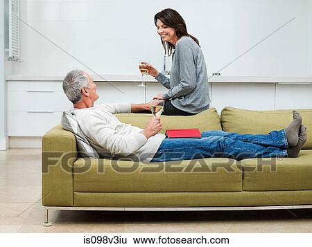 Mature couple sitting on sofa with wine View Large Photo Image Stock Photograph - Mature couple sitting on sofa with wine. Fotosearch