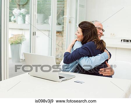 Mature couple using laptop, embracing View Large Photo Image Stock Photo - Mature couple using laptop, embracing. Fotosearch